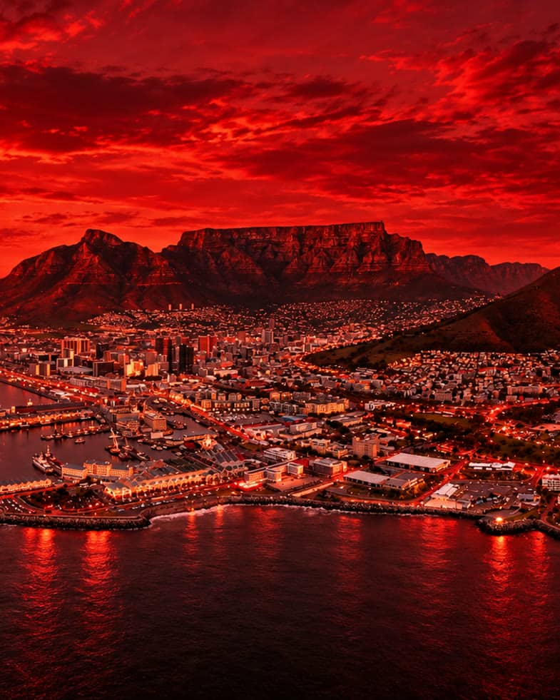 Aerial view of Cape Town at sunset with Table Mountain behind the city bowl, the V&A Waterfront and the stadium below